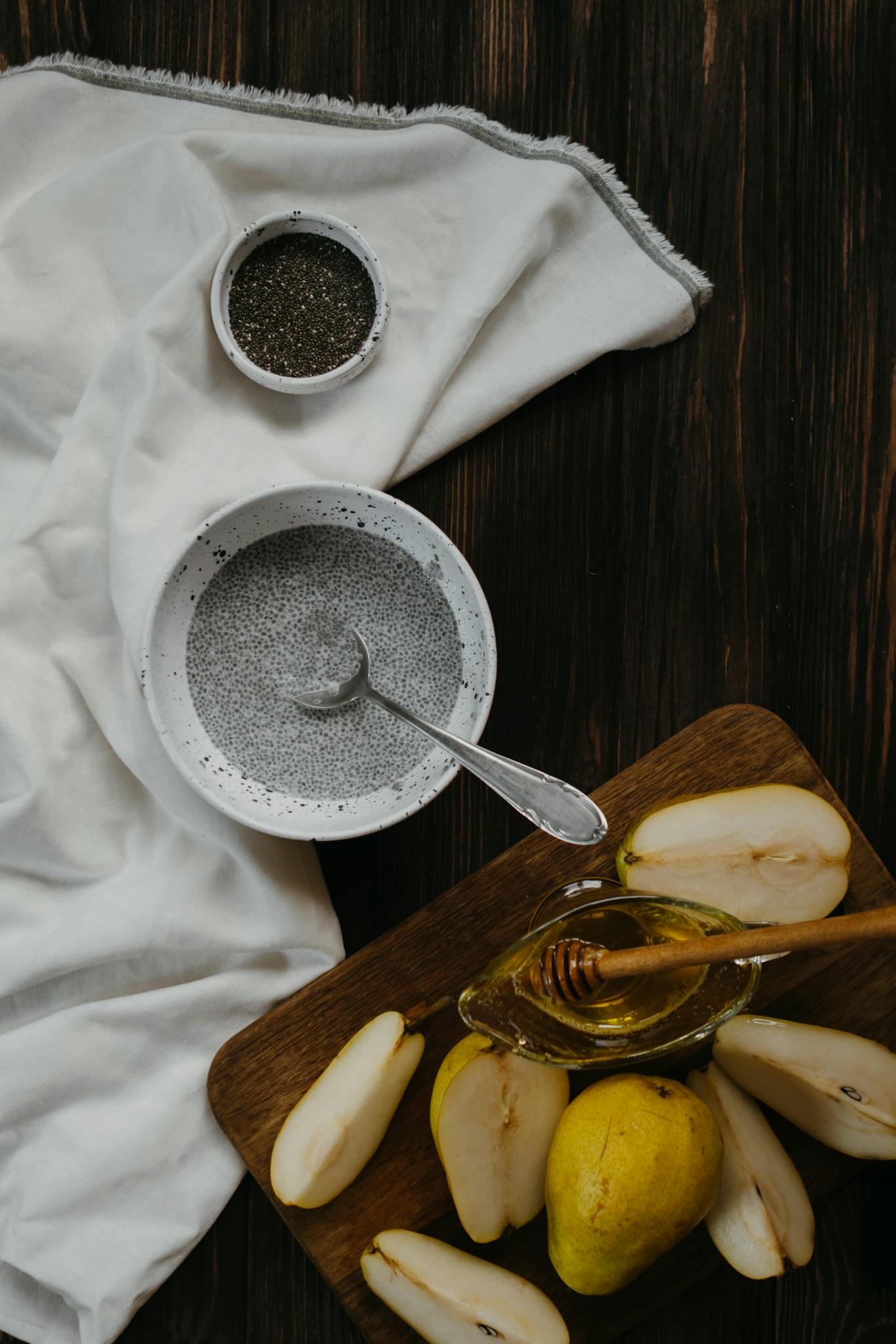 A delicious homemade chia pudding with fresh pears and honey, set on a rustic wooden table.